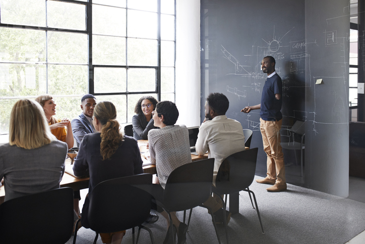 Amputated businessman explaining while female and male coworker sitting in board meeting at workplace